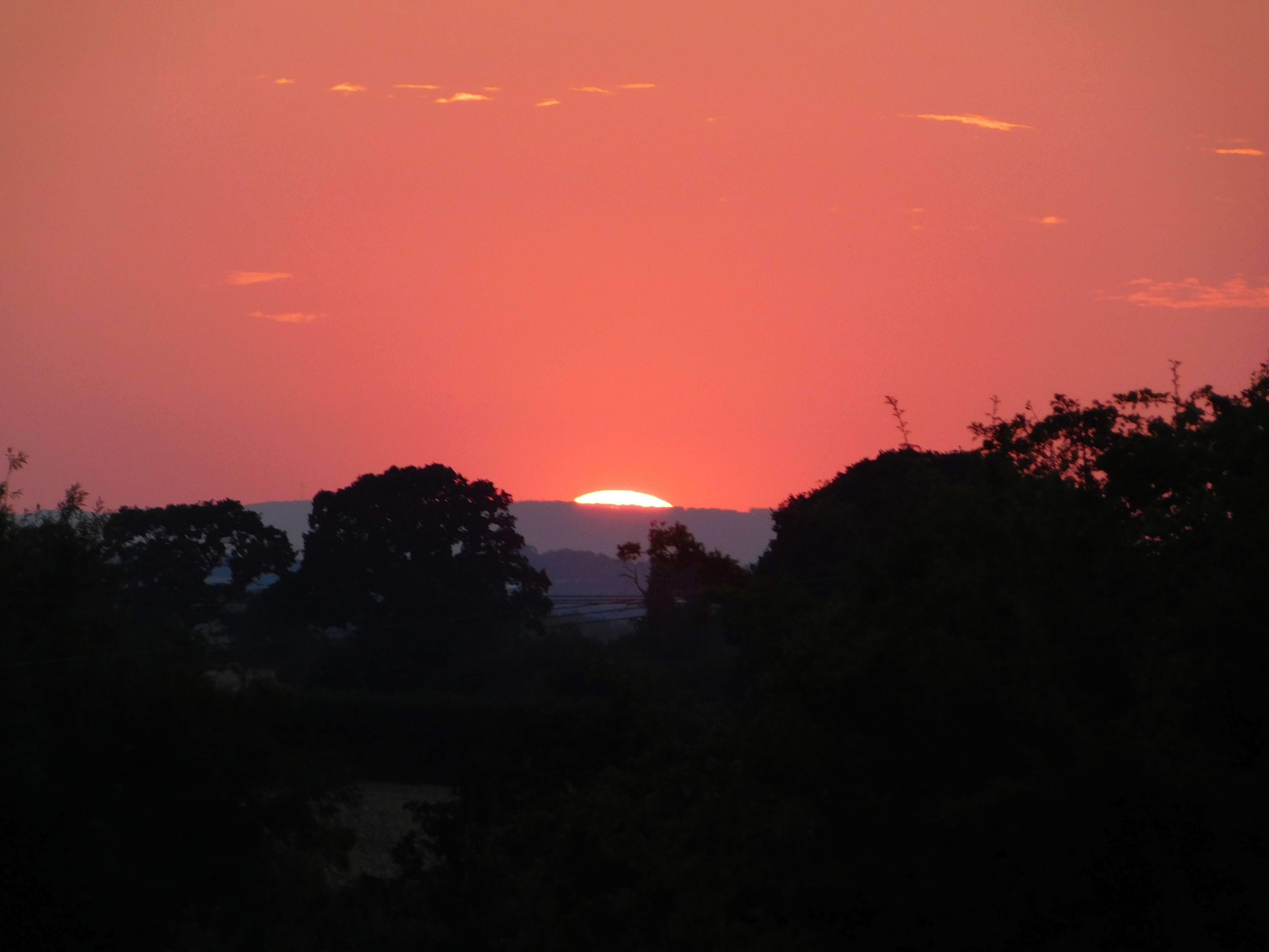 The sunset behind some rolling hills